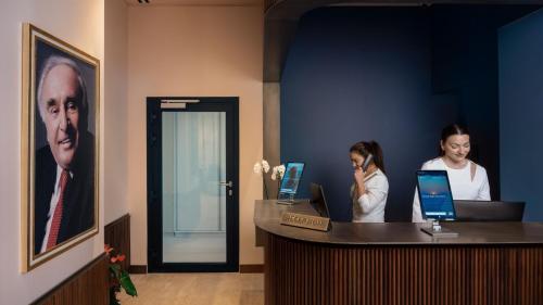 two women sitting at a reception desk with their laptops at Mitsis N'U Piraeus Port in Piraeus