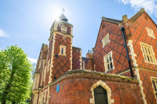 an old brick building with a clock tower at Tower Cottage - Medieval Grid Townhouse in Bury Saint Edmunds