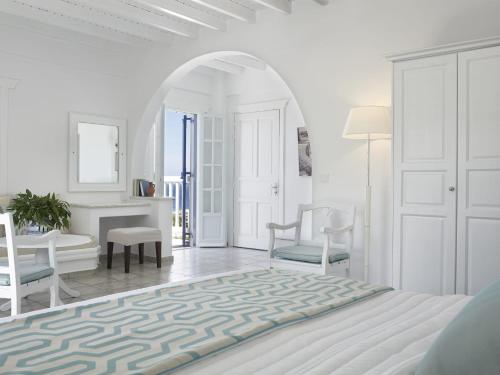 a white bedroom with a bed and a table and chairs at San Marco Hotel and Villas in Houlakia