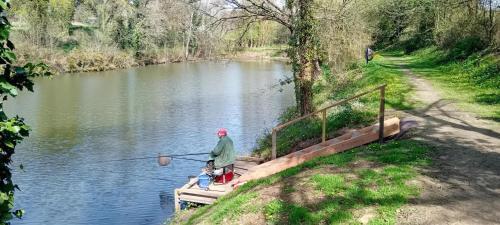 a man is standing on a dock with a fishing rod at Gîte du jardin de pierre in Pléhédel