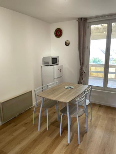 une salle à manger avec une table et des chaises et un micro-ondes dans l'établissement Le paisible F2 à 300 m du centre ville, à LʼHay-les-Roses