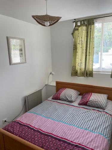 une chambre avec un lit avec deux oreillers dans l'établissement Le paisible F2 à 300 m du centre ville, à LʼHay-les-Roses