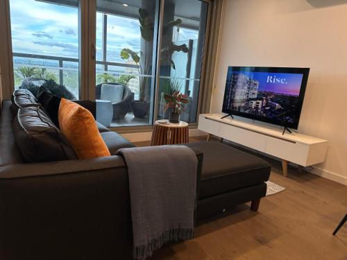 a living room with a couch and a flat screen tv at Rise to the top! in Melbourne