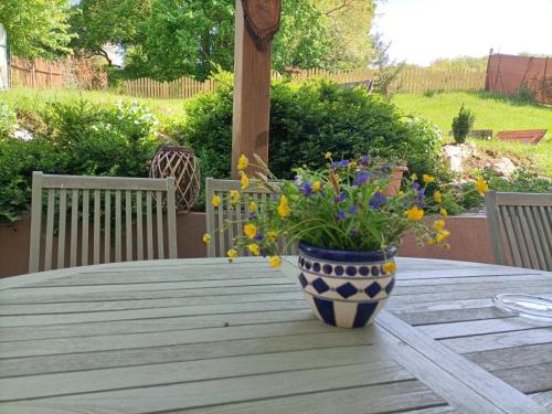 a blue and white vase on a wooden table with flowers at Liget Vendégház in Szokolya