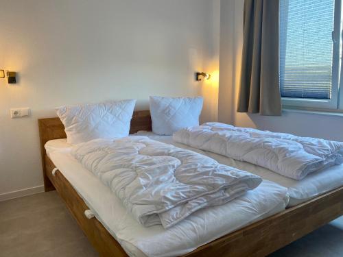 two unmade beds in a room with a window at Ferienwohnung Nordwind - Haus Seeschwalbe in Wangerland