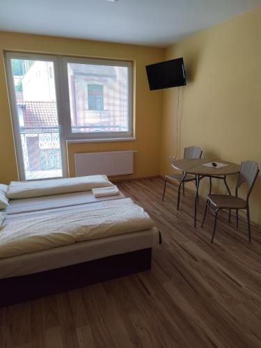 a bedroom with a bed and a table with chairs at Apartmány ORAVA-EDDA in Trenčianske Teplice