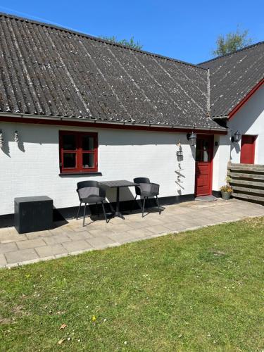 un patio con mesa y sillas frente a un edificio blanco en Sølystvej 16B, en Saeby