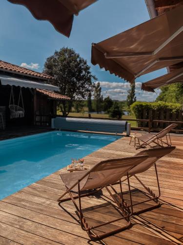 une terrasse en bois avec deux chaises et une piscine dans l'établissement Locarmel, à Gouts