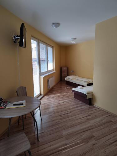 a room with two beds and a table and a window at Apartmány ORAVA-EDDA in Trenčianske Teplice