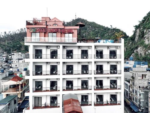 a tall white building with a house on top of it at Cat Ba Viet Hoa Hotel & Residence - Pool & Bar in Cat Ba