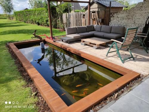 uno stagno di koi in un cortile con un divano e un tavolo di Luxury eco home with large garden and lots of light a Ons Belang
