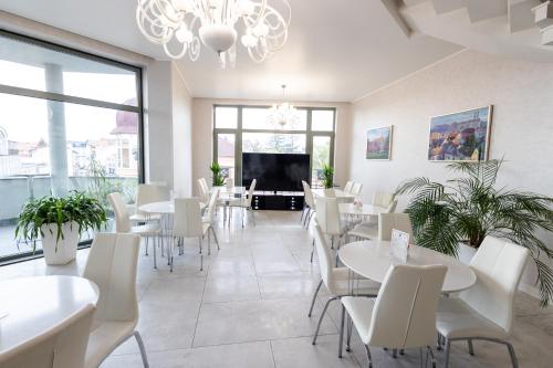 a restaurant with white tables and chairs and a tv at Nicole in Uzhhorod