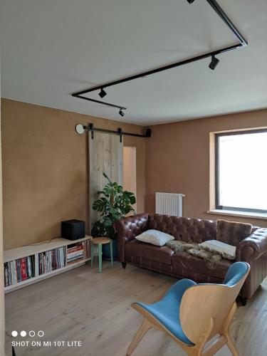 a living room with a brown leather couch and a window at Luxury eco home with large garden and lots of light in Ons Belang