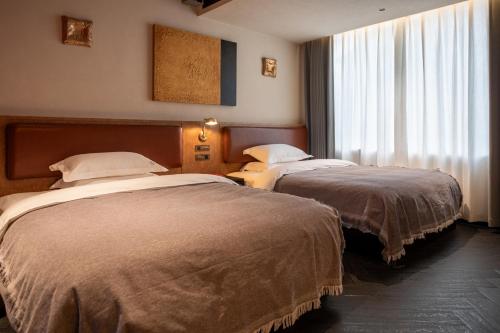a hotel room with two beds and a window at SIXI CANGSHAN MOUNTAINS GOLDEN SUNRISE MIRROR OF THE SKY SOUND SLEEP HOTEL DALI ANCIENT CITy in Dali