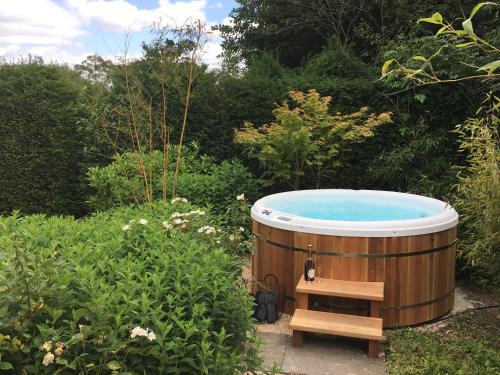 a jacuzzi tub in a garden with a bench at Kingscote Park House in Kingscote
