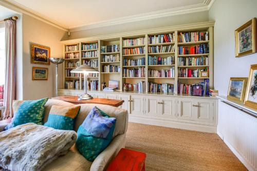 a living room with a couch and bookshelves at Kingscote Park House in Kingscote