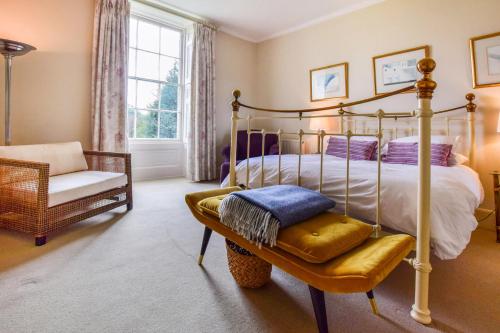 a bedroom with a bed and a chair and a window at Kingscote Park House in Kingscote