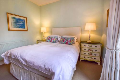 a bedroom with a white bed with two pillows at Kingscote Park House in Kingscote