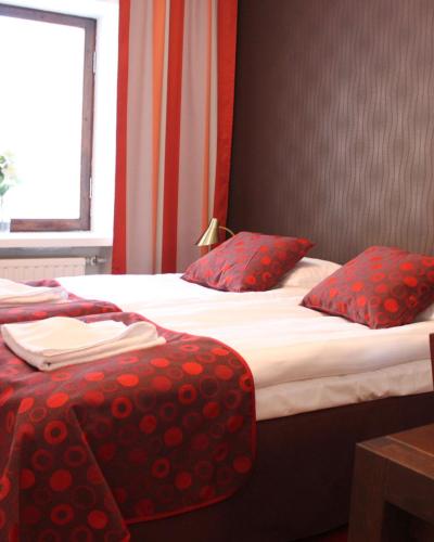 two beds in a hotel room with red pillows at Art Hostel Honkahovi in Mänttä