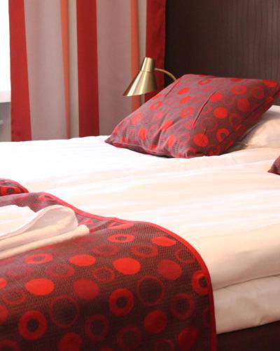 two beds with red and white sheets and a lamp at Art Hostel Honkahovi in Mänttä