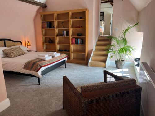 a bedroom with a bed and a chair and stairs at Kingscote Park House in Kingscote
