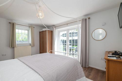 a bedroom with a white bed and a window at Felin Traeth Cottage in Rhosneigr