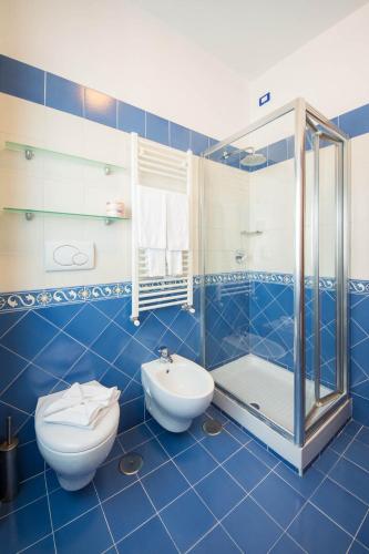 a blue tiled bathroom with a toilet and a shower at Angelina Residence in Maiori