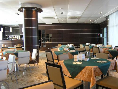 una sala da pranzo con tavoli, sedie e camino di Dado Hotel International a Parma