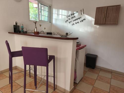 a kitchen with a bar with a purple stool at Barbara in La Trinité