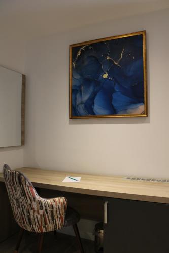 a desk with a chair and a painting on a wall at El Aziz Inn in Cheraga