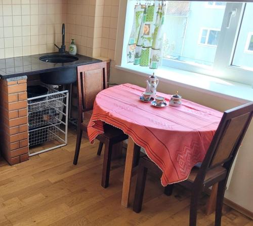 a table with a pink table cloth on it in a kitchen at Peresõbralik korter Kuressaare kesklinnas in Kuressaare