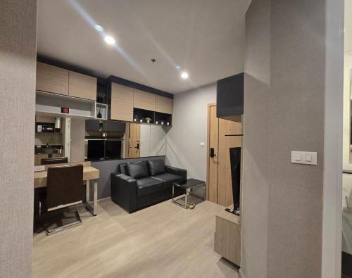 a living room with a black couch and a kitchen at Lisa house&home #nearcentralfestival in Hat Yai