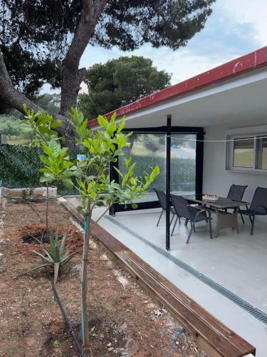 Un patio con una mesa y sillas y un árbol. en Villa ADAM, en Artemida