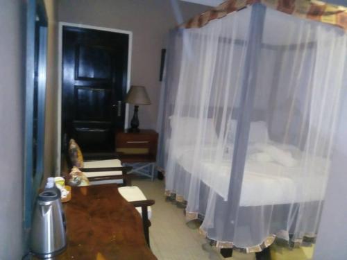 a bedroom with a bed with white curtains and a table at Living Waters Resort in Jinja