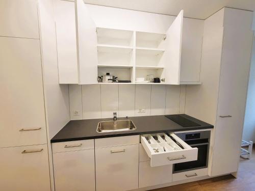 a white kitchen with a sink and white cabinets at Zurich City Center Apartments next to Zurich HB Main Train Station LA - Self Checkin in Zürich