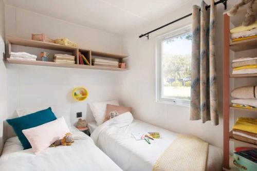 een kleine slaapkamer met twee bedden en een raam bij Camping 4 étoiles - Piscine - ccb0dhf in Saint-Denis