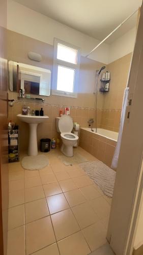 a bathroom with a toilet and a sink and a tub at Unwind Kìśśornega - 2 Bedroom Apartment in Kissonerga