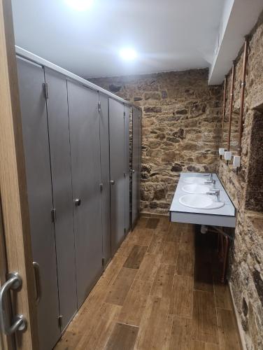 a bathroom with two sinks and a stone wall at Albergue Freixo in Palas de Rei