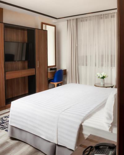 a bedroom with a large white bed and a desk at Villa Misk Alkhobar in Al Khobar