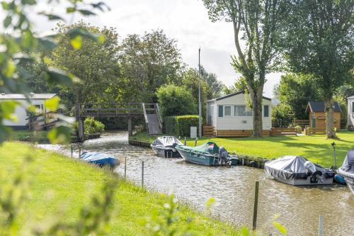 a group of boats are docked in a river at Waddenlodge Deluxe in Harlingen