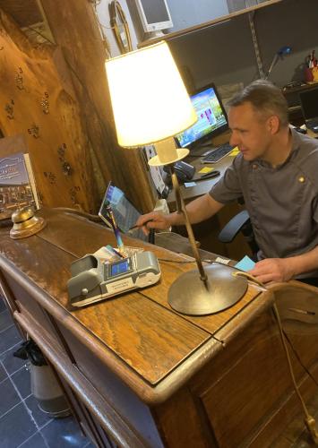 a man sitting at a desk with a lamp on a table at Auberge de L'an 1600 in Bouillon