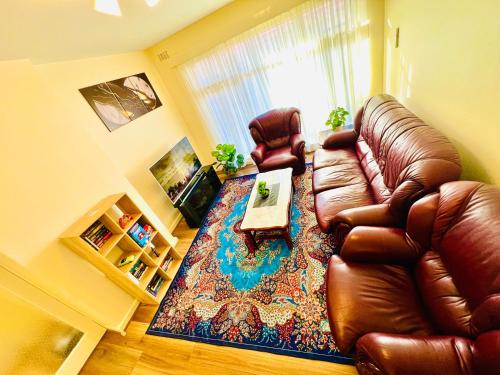 a living room with a leather couch and a table at Spacious and cosy 2BR in Balwyn in Balwyn