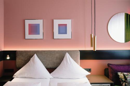 a bedroom with pink walls and a bed with white pillows at Westend Hotel (non-smoking) in Munich