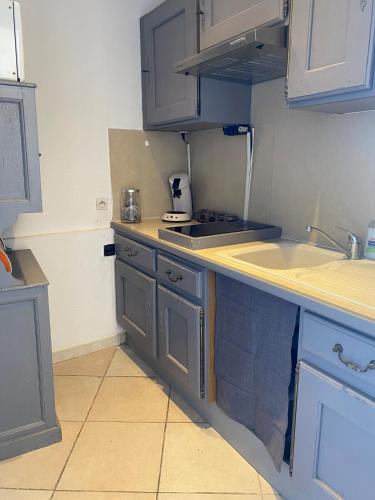 une cuisine avec des armoires bleues et un évier dans l'établissement appartement de charme, à Lançon-Provence