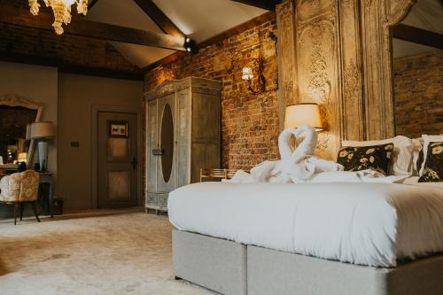 a bedroom with a large white bed and a brick wall at Le Petit Chateau & William de Percy in Otterburn