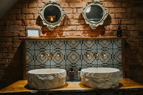 two stone stools on a table with mirrors on a brick wall at Le Petit Chateau & William de Percy in Otterburn
