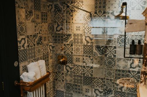 a bathroom with a tiled wall with towels at Le Petit Chateau & William de Percy in Otterburn