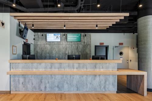 a lobby with a large concrete counter with chairs at ibis budget Madrid Aeropuerto in Madrid
