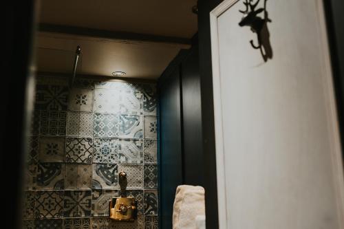 a bathroom with a shower with blue and white tiles at Le Petit Chateau & William de Percy in Otterburn