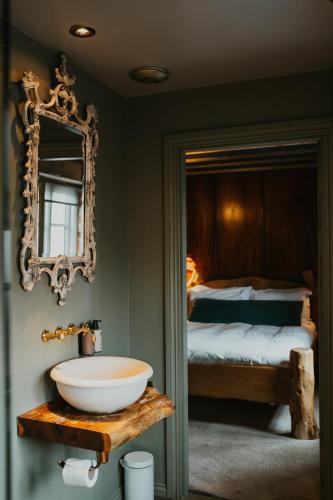 a bathroom with a sink and a bed at Le Petit Chateau & William de Percy in Otterburn